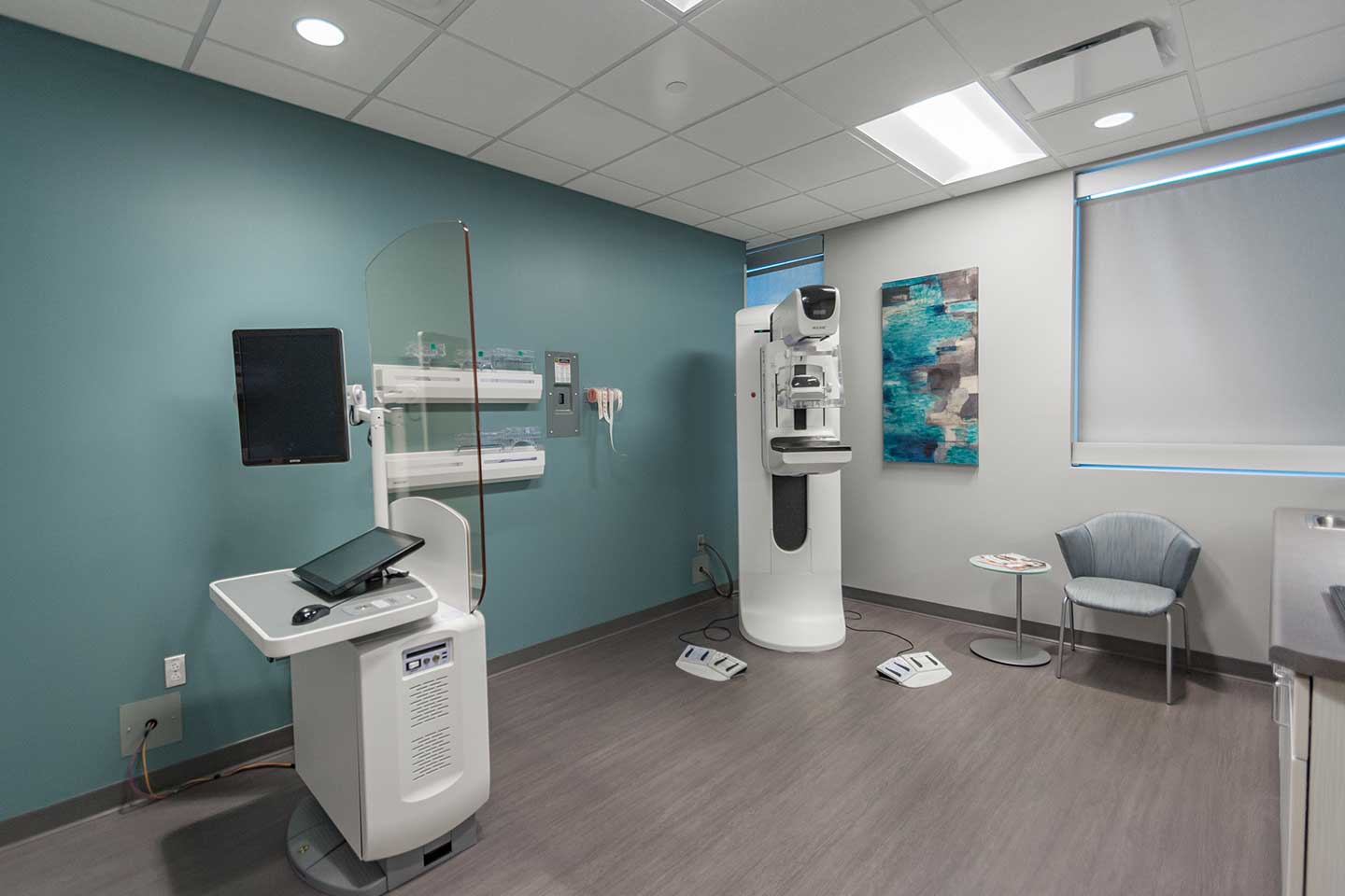 Modern mammography suite with a digital mammogram machine, workstation, and teal accent wall.