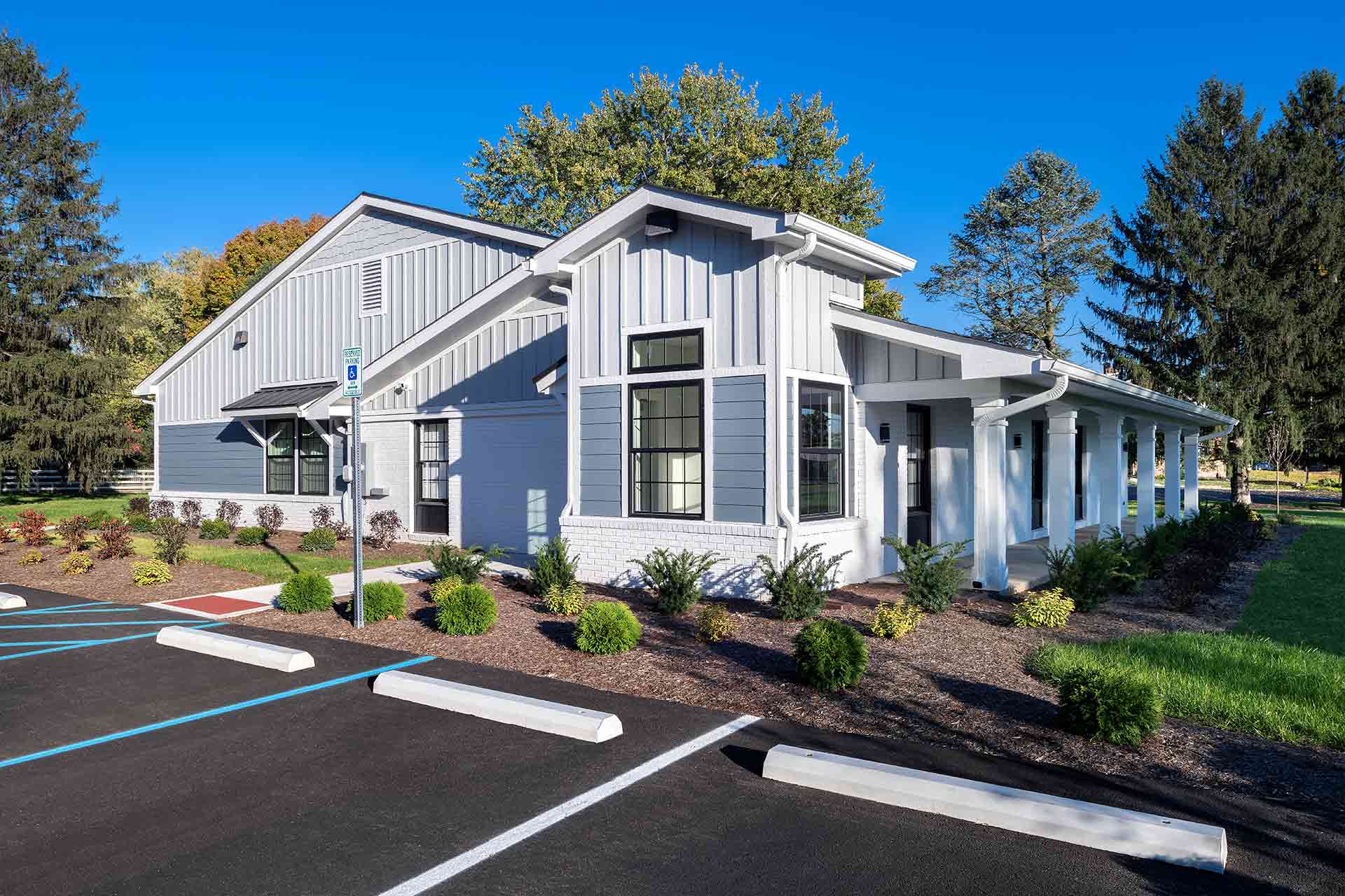 Exterior of a modern light blue and white dental building with a front porch and accessible parking.